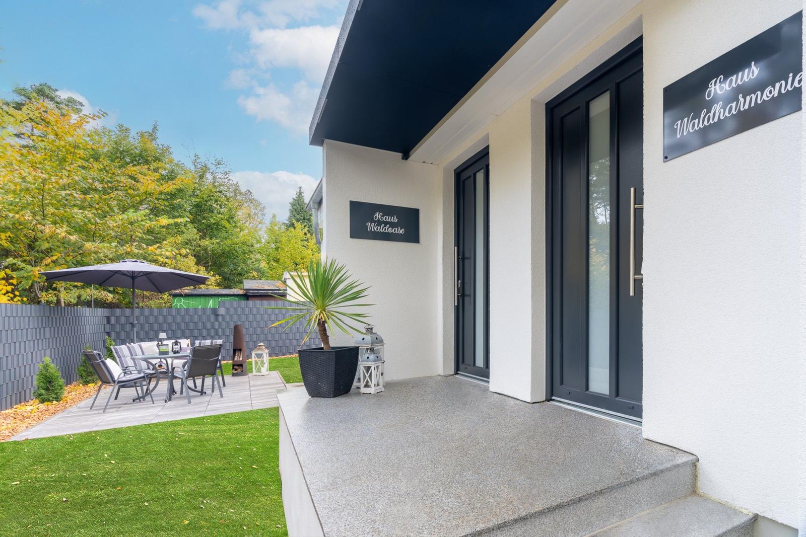 Eingangsbereich mit Terrasse, Garten und Sitzgelegenheiten. Haus Waldharmonie.