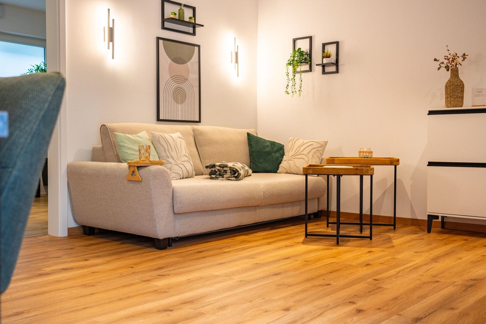 Ein Wohnzimmer mit Sofa, Kissen, Holzboden und Wanddekoration.