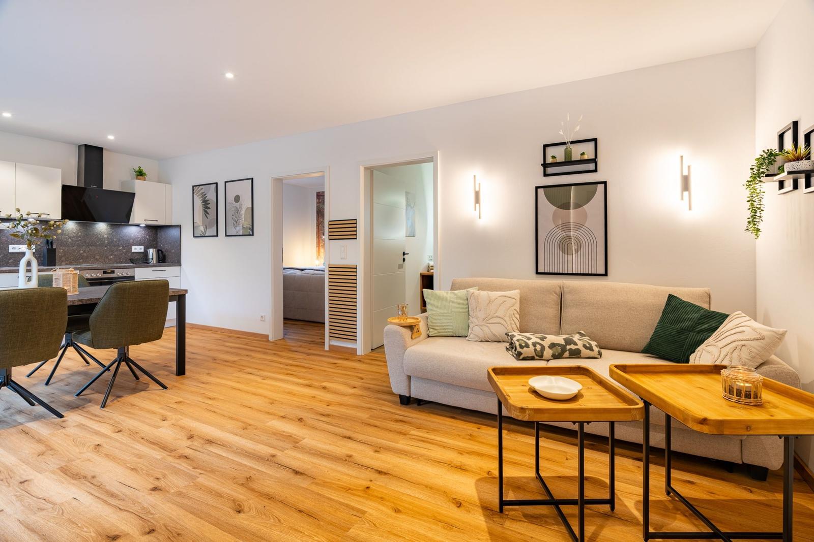 Wohnzimmer mit Sofa, Tischen und Blick in Küche und Schlafzimmer.