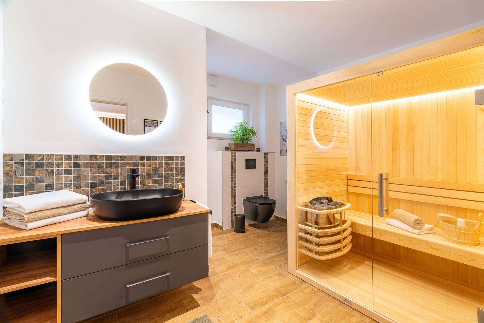 Bad mit Sauna, Waschbecken und Toilette.