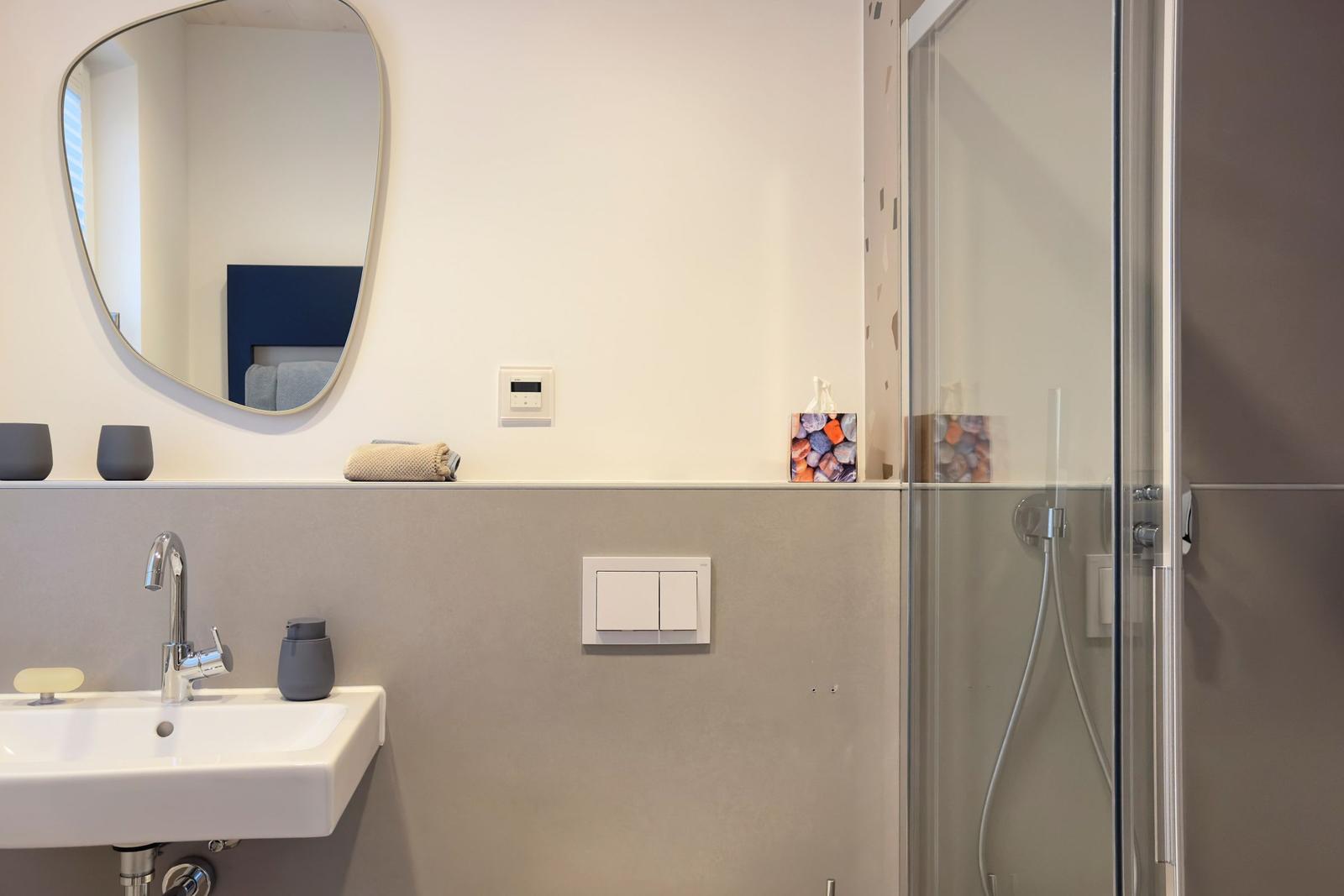 Badezimmer mit Dusche, Waschbecken und Spiegel.