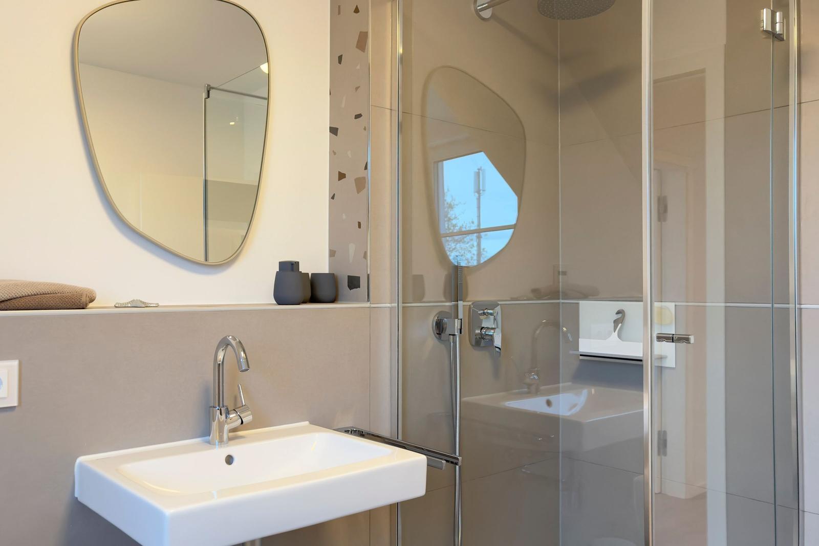 Badezimmer mit Waschbecken, Spiegel und Dusche.