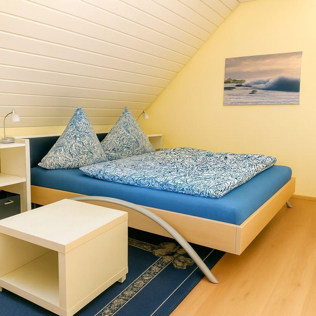 Schlafzimmer mit Bett, Nachttischen und Wandbild.