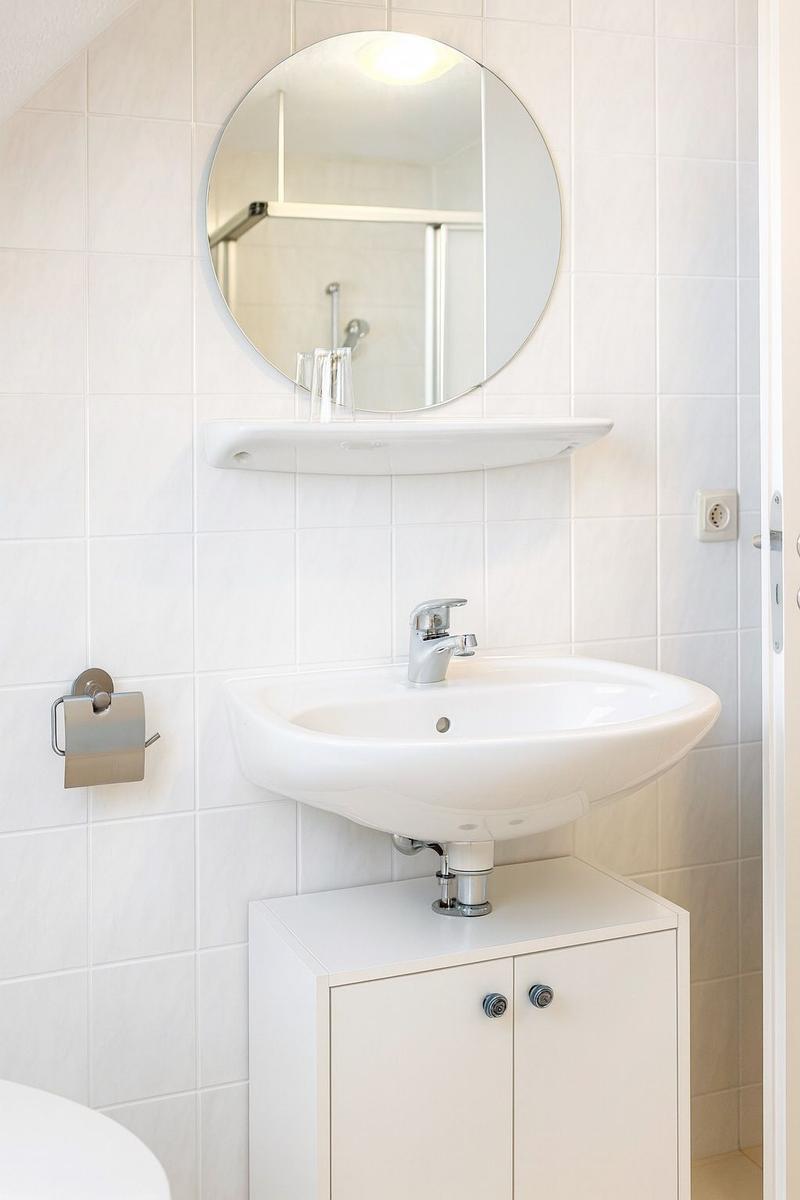 Bad mit Waschbecken, Spiegelschrank und Dusche.