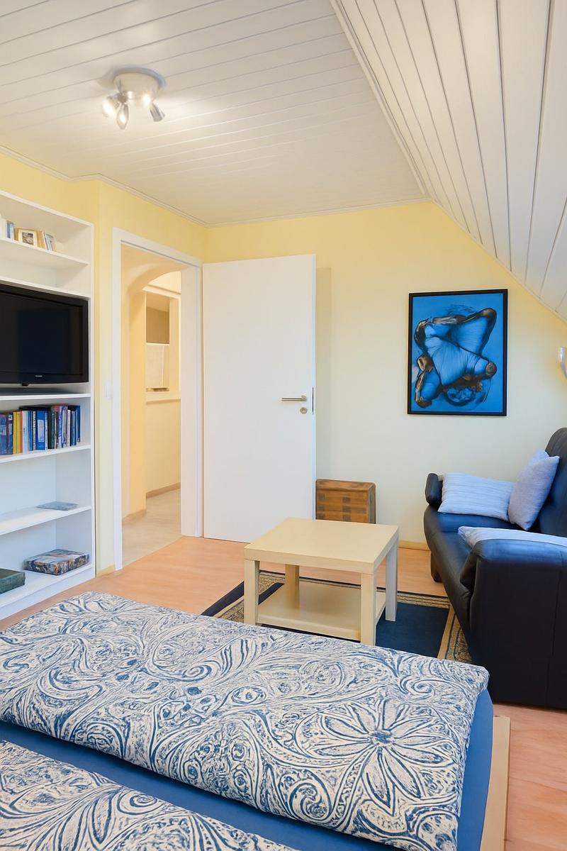 Schlafzimmer mit Bett, Sofa und Fernseher an der Wand.