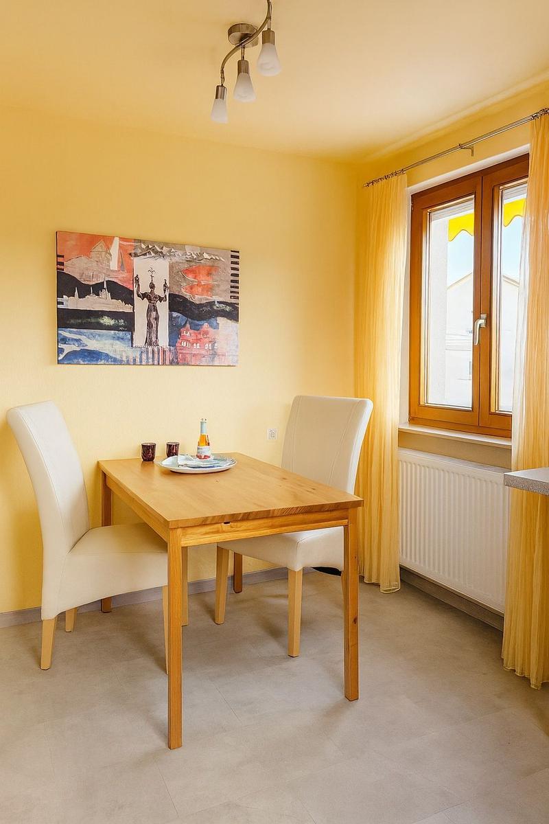 Esszimmer mit Holztisch, zwei Stühlen, Wandbild und Fenster.