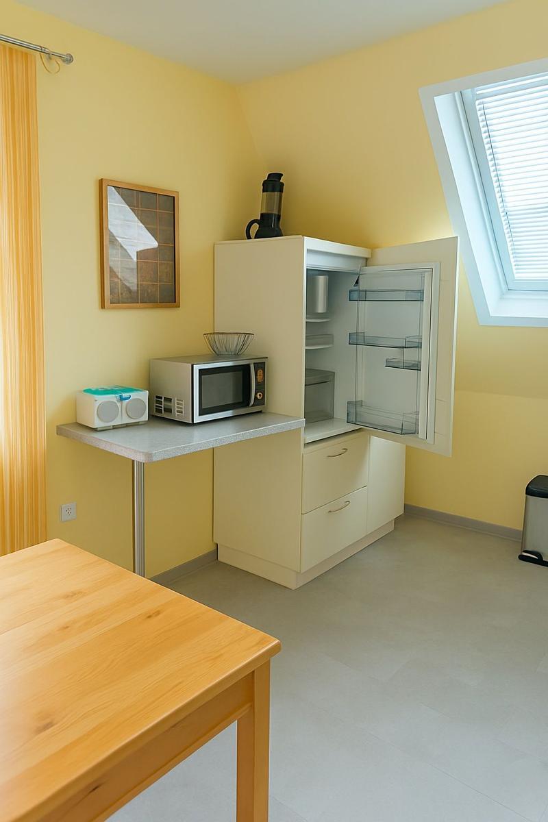 Küche mit Kühlschrank, Mikrowelle und Tisch.