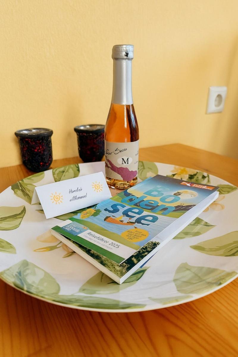 Auf einem Tisch steht eine Flasche, ein Buch und zwei Gläser.