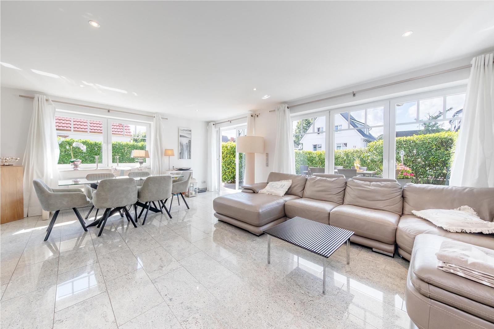 Großes Wohn- und Esszimmer mit Sofa, Tisch und Fenstern.