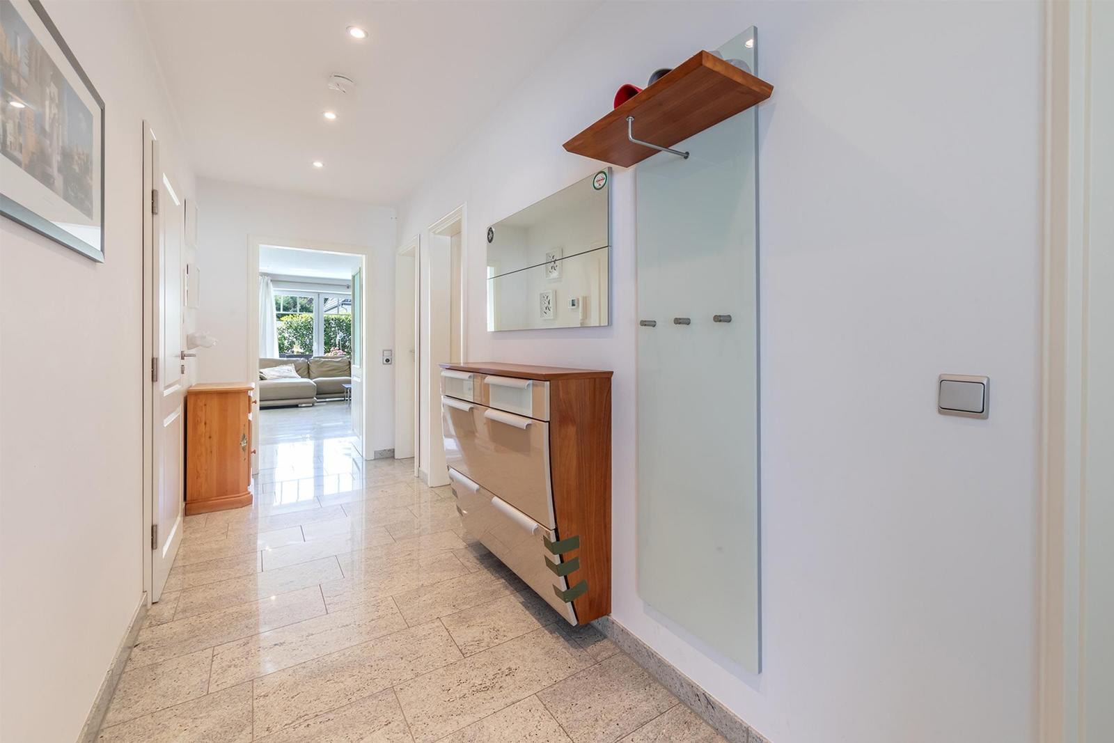 Flur mit Garderobe, Spiegel und Blick in Wohnbereich.