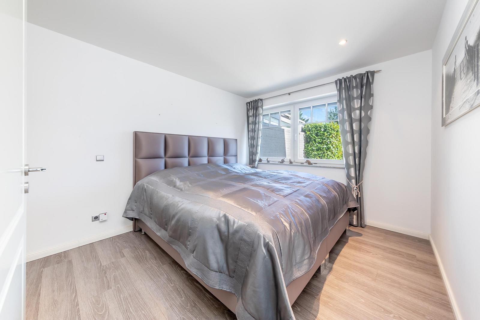 Schlafzimmer mit Bett, Fenster und Holzboden.