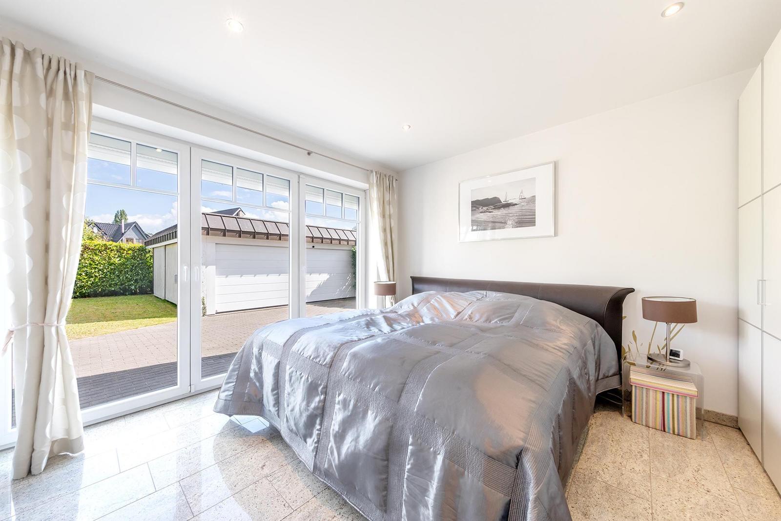 Schlafzimmer mit Bett, Schrank und Blick auf die Terrasse.