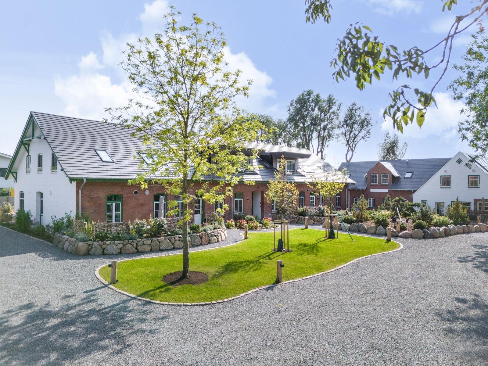 House with garden, playground, and paved path under blue sky.