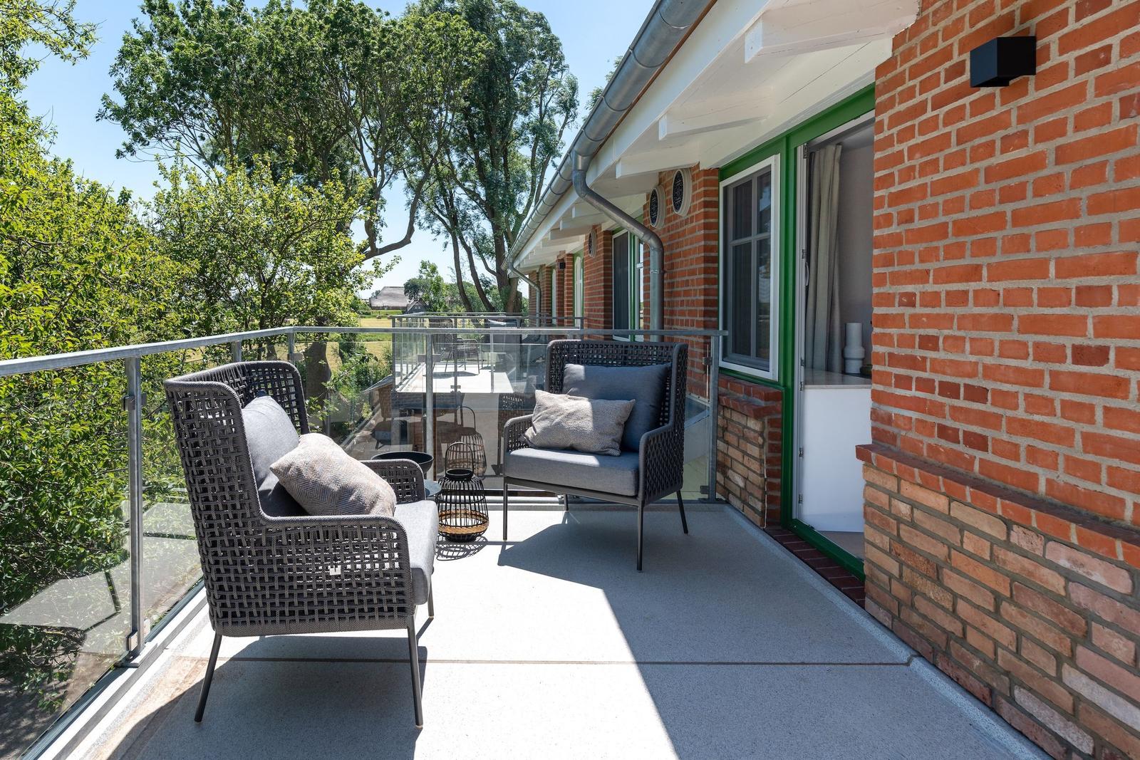 Terrace with two chairs and view of green trees.