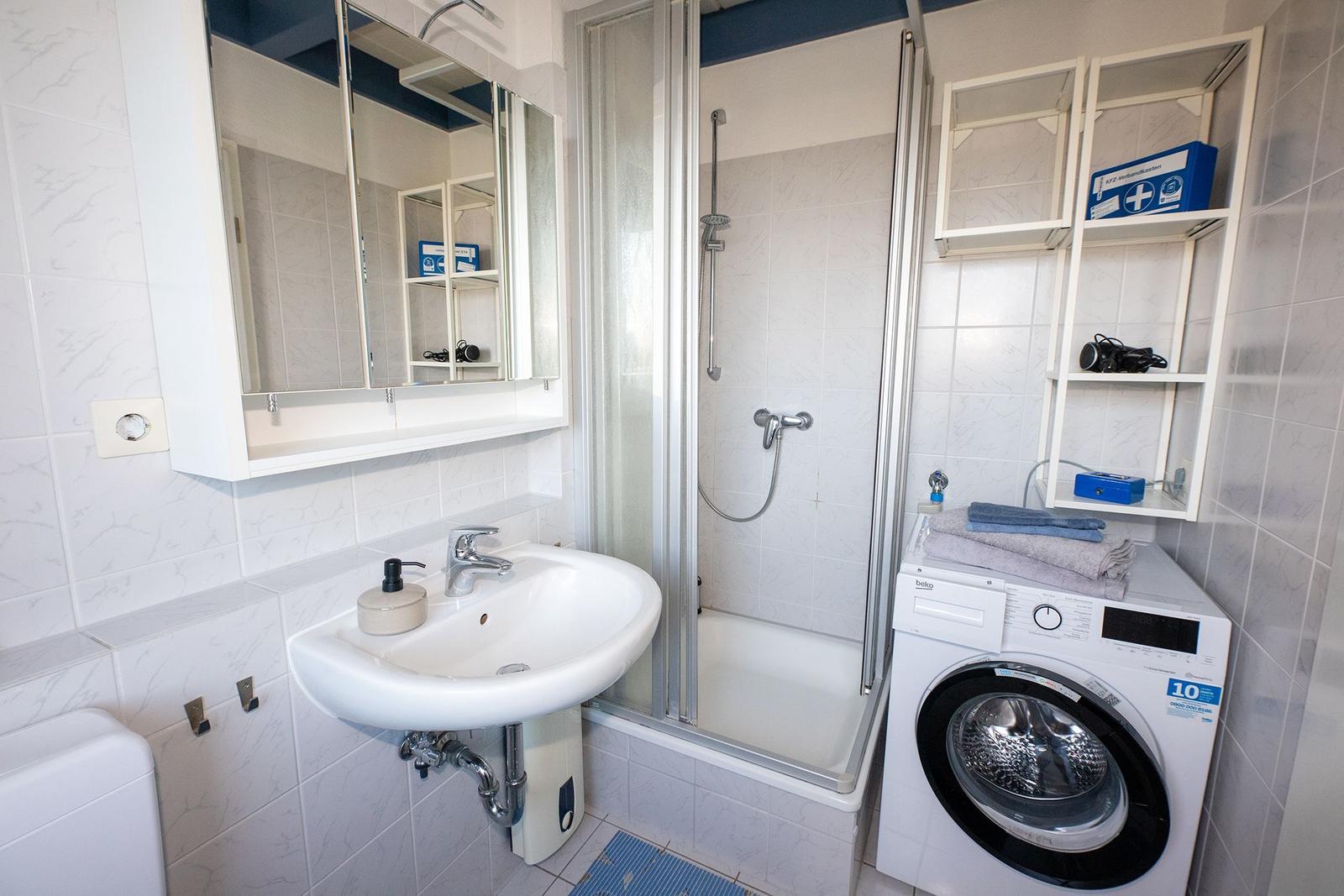 Badezimmer mit Dusche, Waschmaschine und Spiegelkabinett.