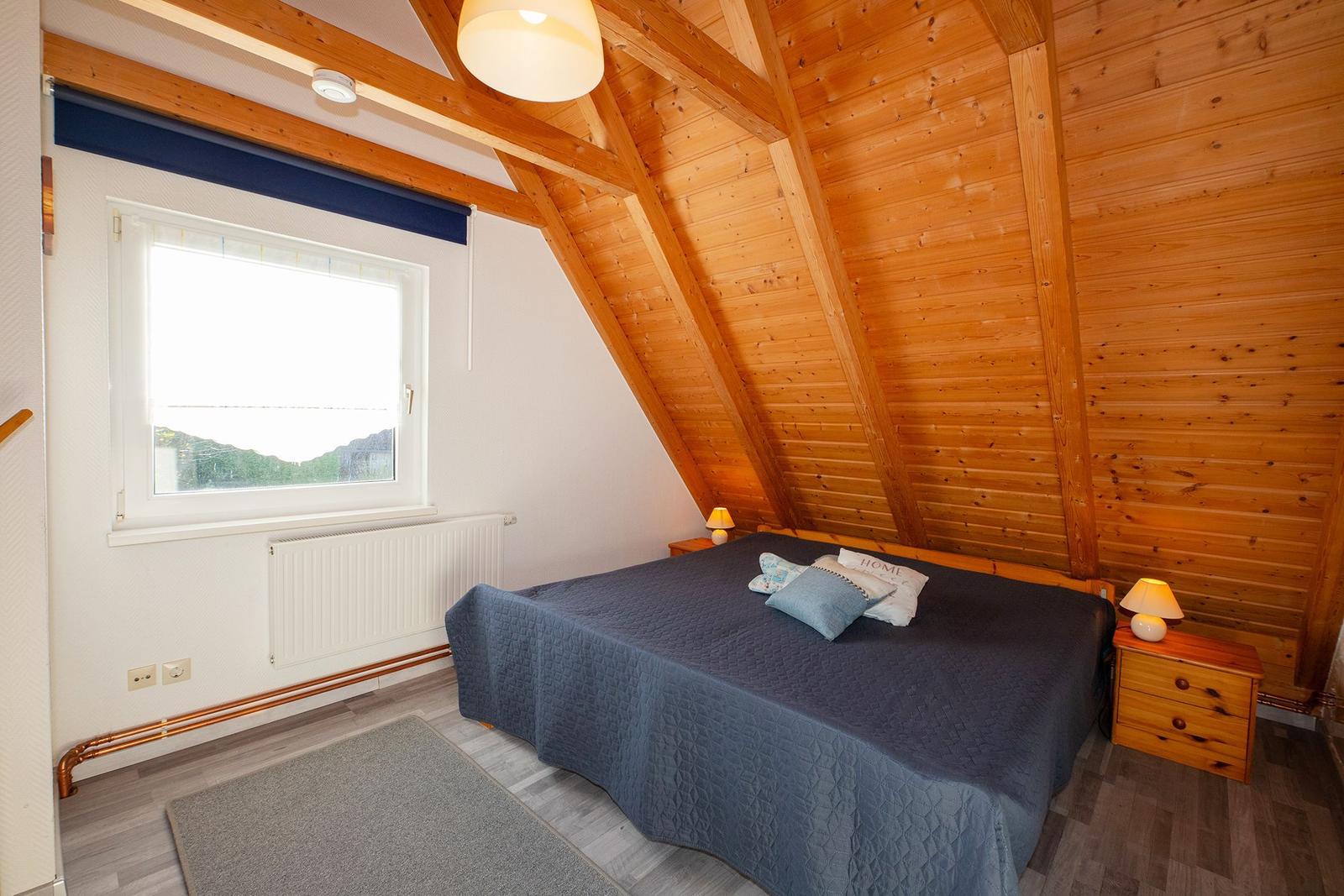 Schlafzimmer mit Holzwand, Bett und Fenster