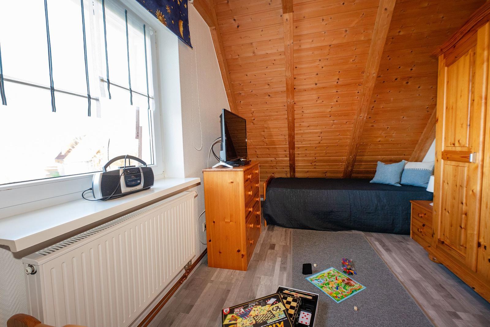 Schlafzimmer mit Holzdecke, Bett, Schrank und TV auf Kommode.