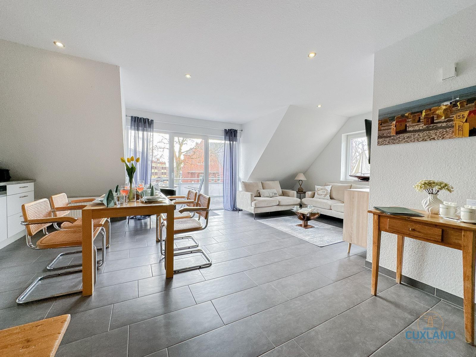 Wohn- und Essbereich mit Sofa, Tisch und Stühlen sowie großem Fenster.