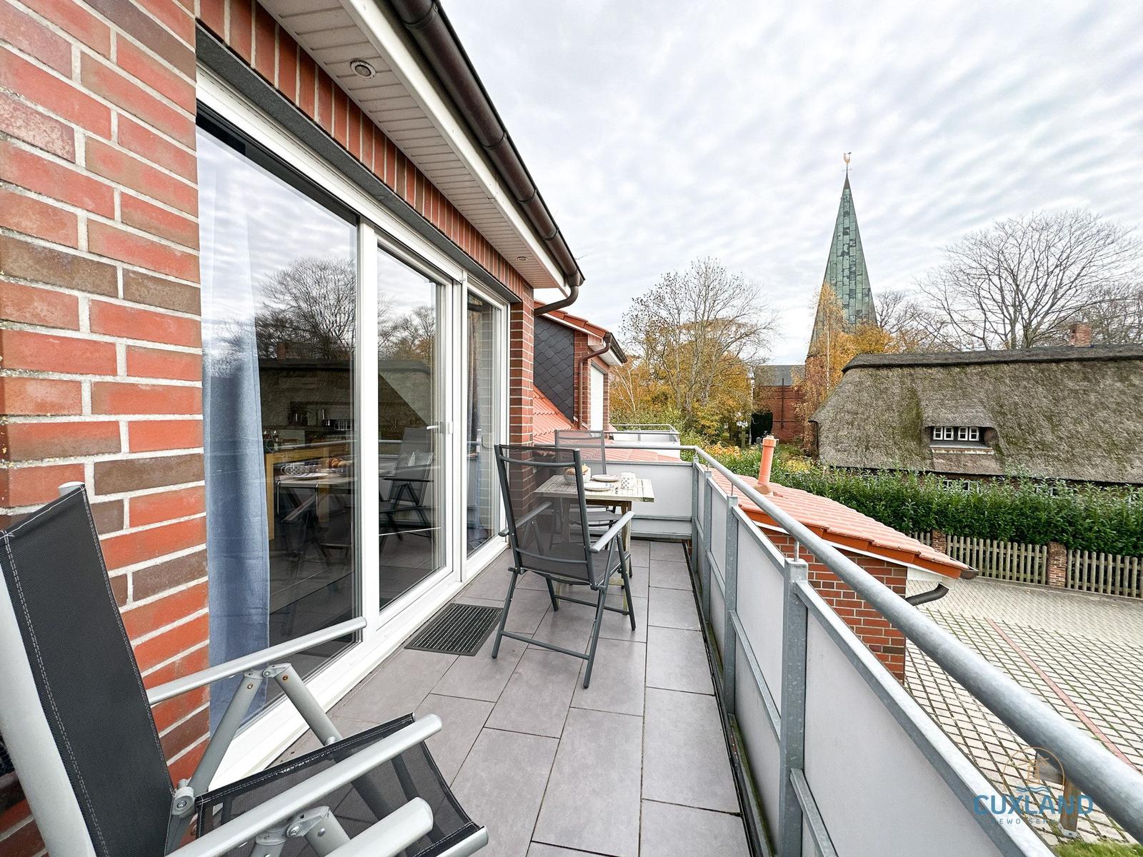 Terrasse mit Tisch, Stühlen und Blick auf Kirche und Dach