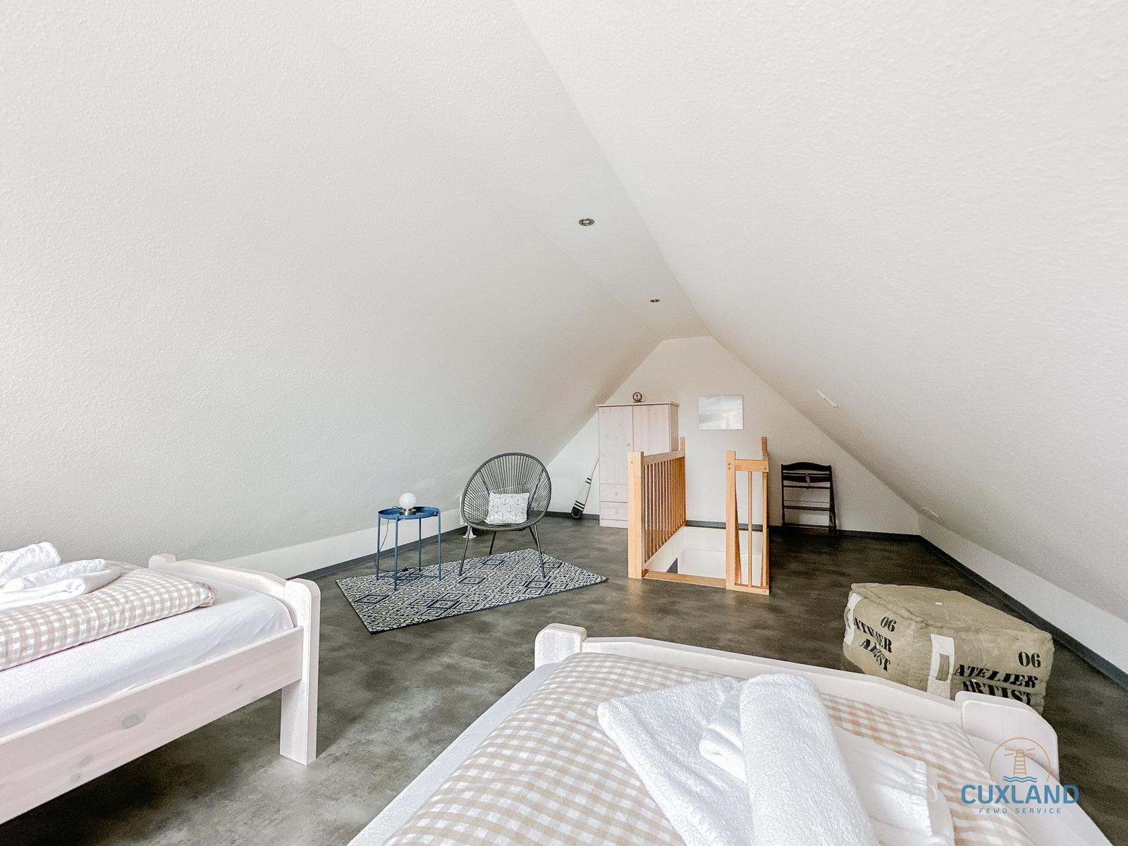 Zwei Betten, Sitzgelegenheit und Babybett in Dachschrägenzimmer