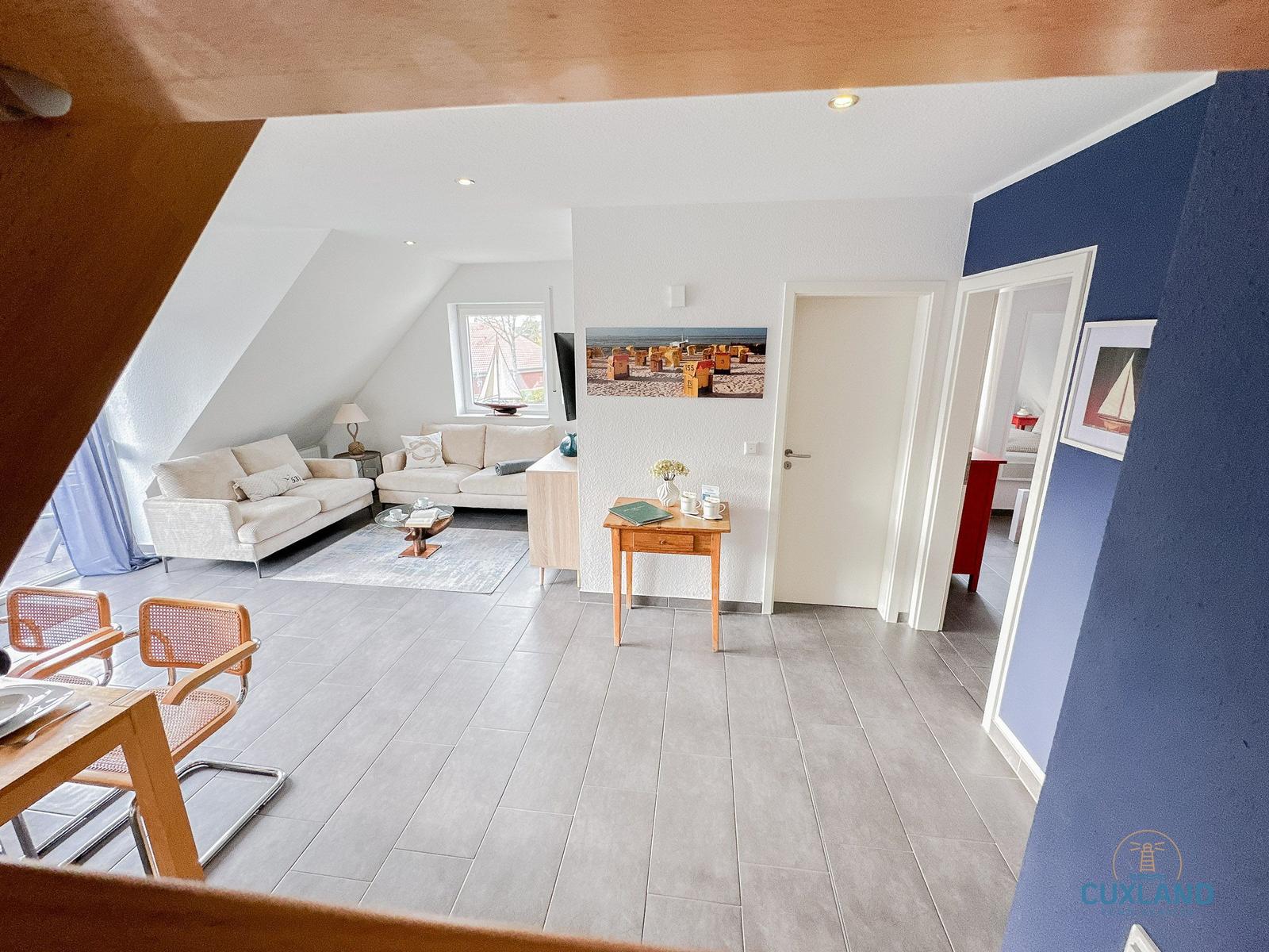 Wohnung mit Wohn- und Essbereich, Sofa, Tisch und Stühle. Wandbild und Tür sichtbar.