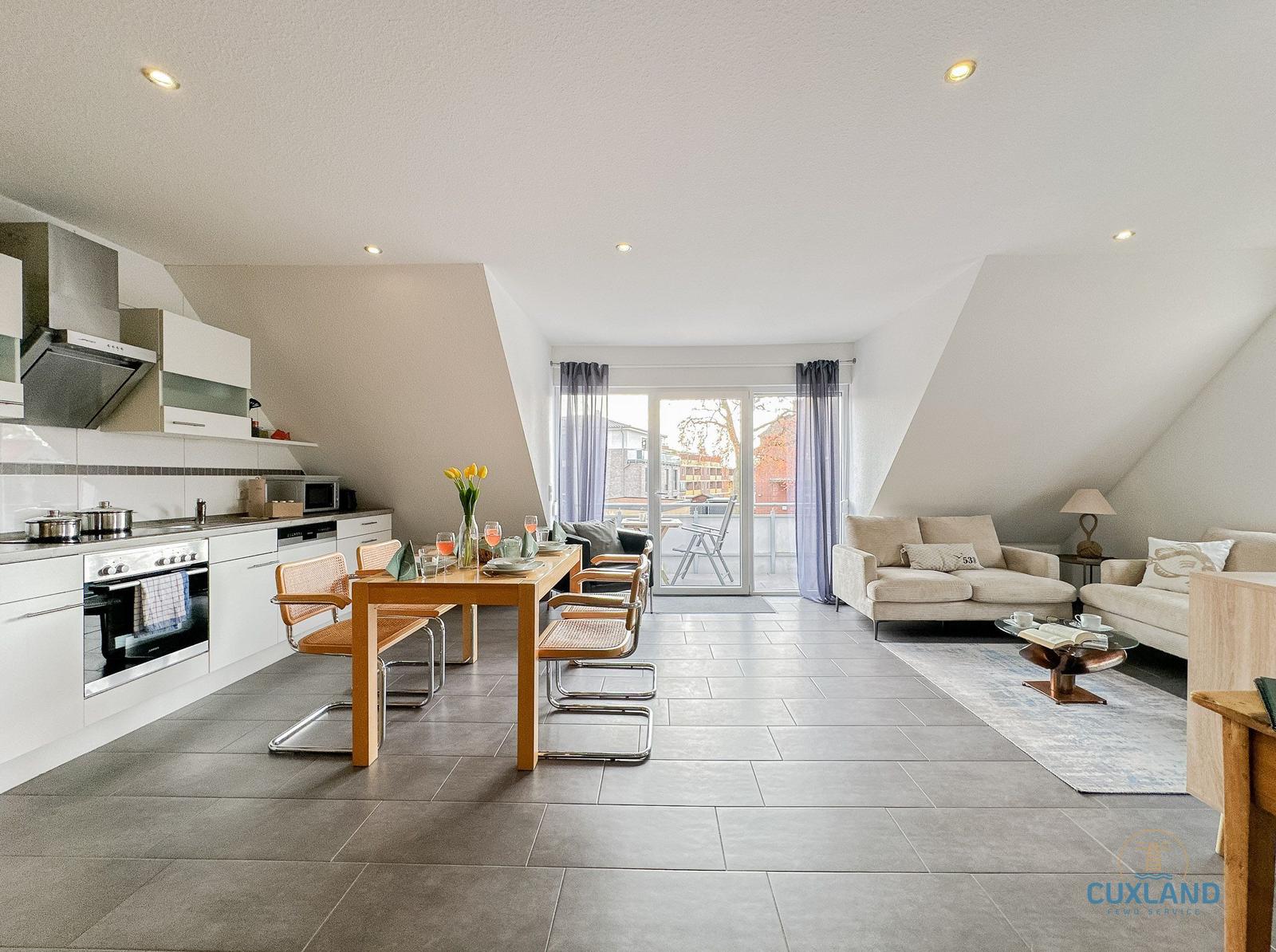 Offener Raum mit Küche, Essbereich und Wohnbereich. Balkon mit Sitzgelegenheit.