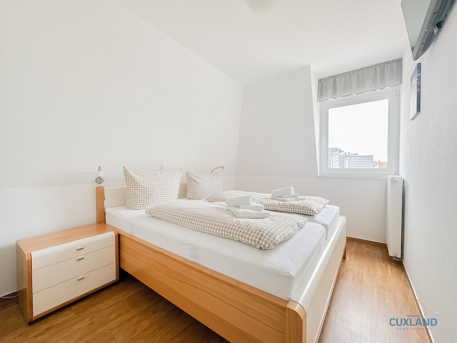 Schlafzimmer mit Doppelbett, Nachttisch und Fenster.