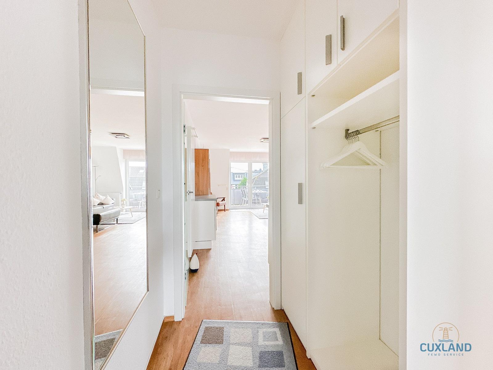 Flur mit Kleiderschrank und Blick in Wohnbereich mit Balkon.