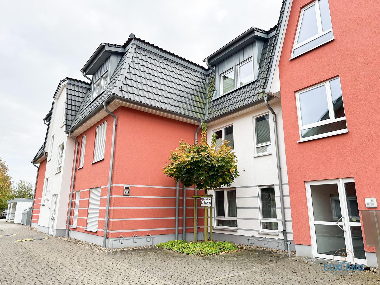 Fassade eines zweistöckigen Hauses mit roten und weißen Wänden und grauem Dach.