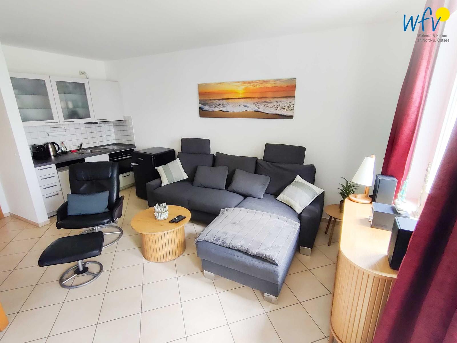 Wohnzimmer mit Sofa, Couchtisch und Küchenbereich.