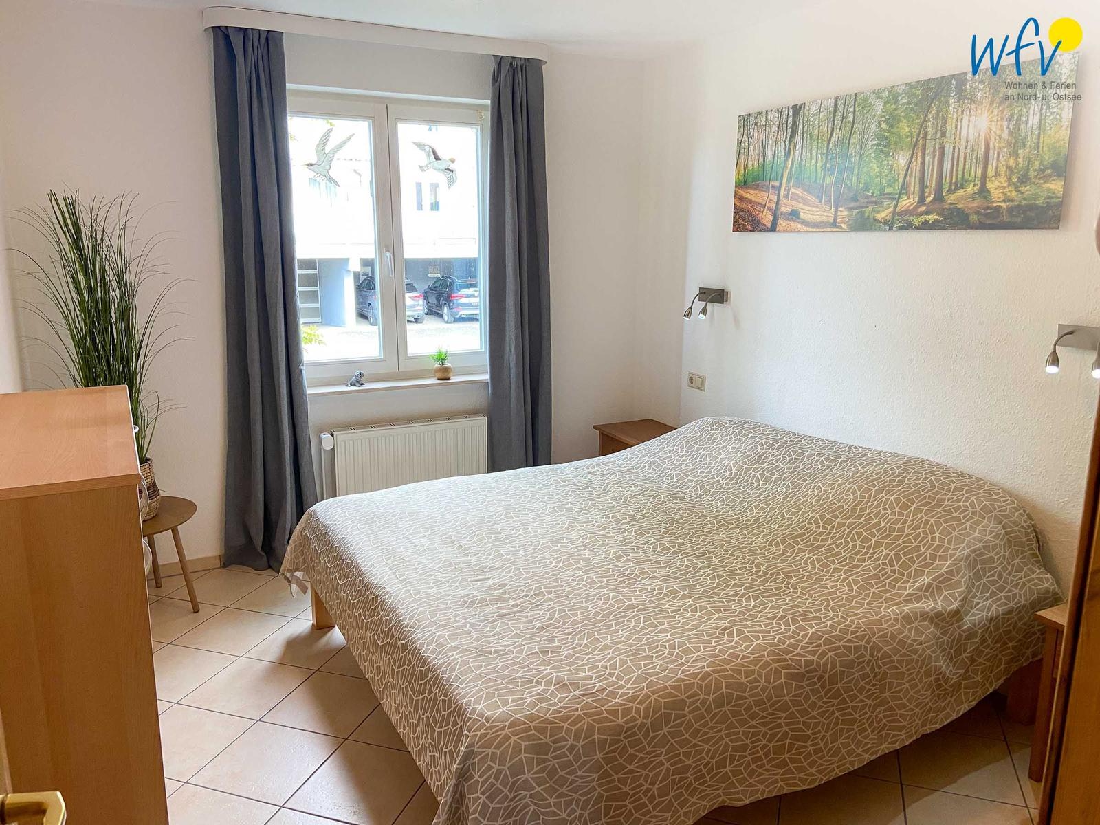 Schlafzimmer mit Bett, Fenster und Wandbild.