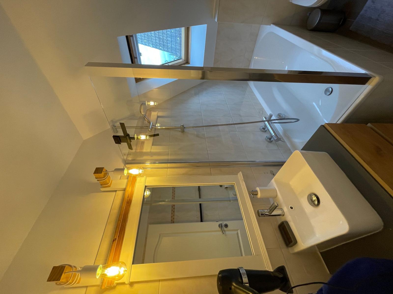 Badezimmer mit Badewanne, Spiegel und Waschbecken.