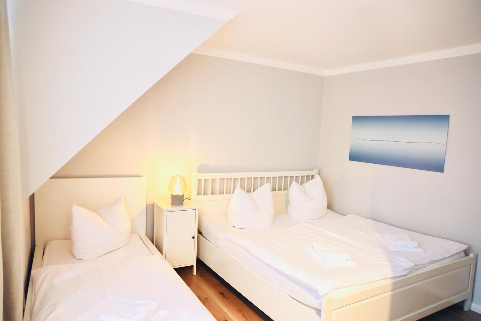 Zimmer mit zwei Betten, Nachttisch und Wandbild.