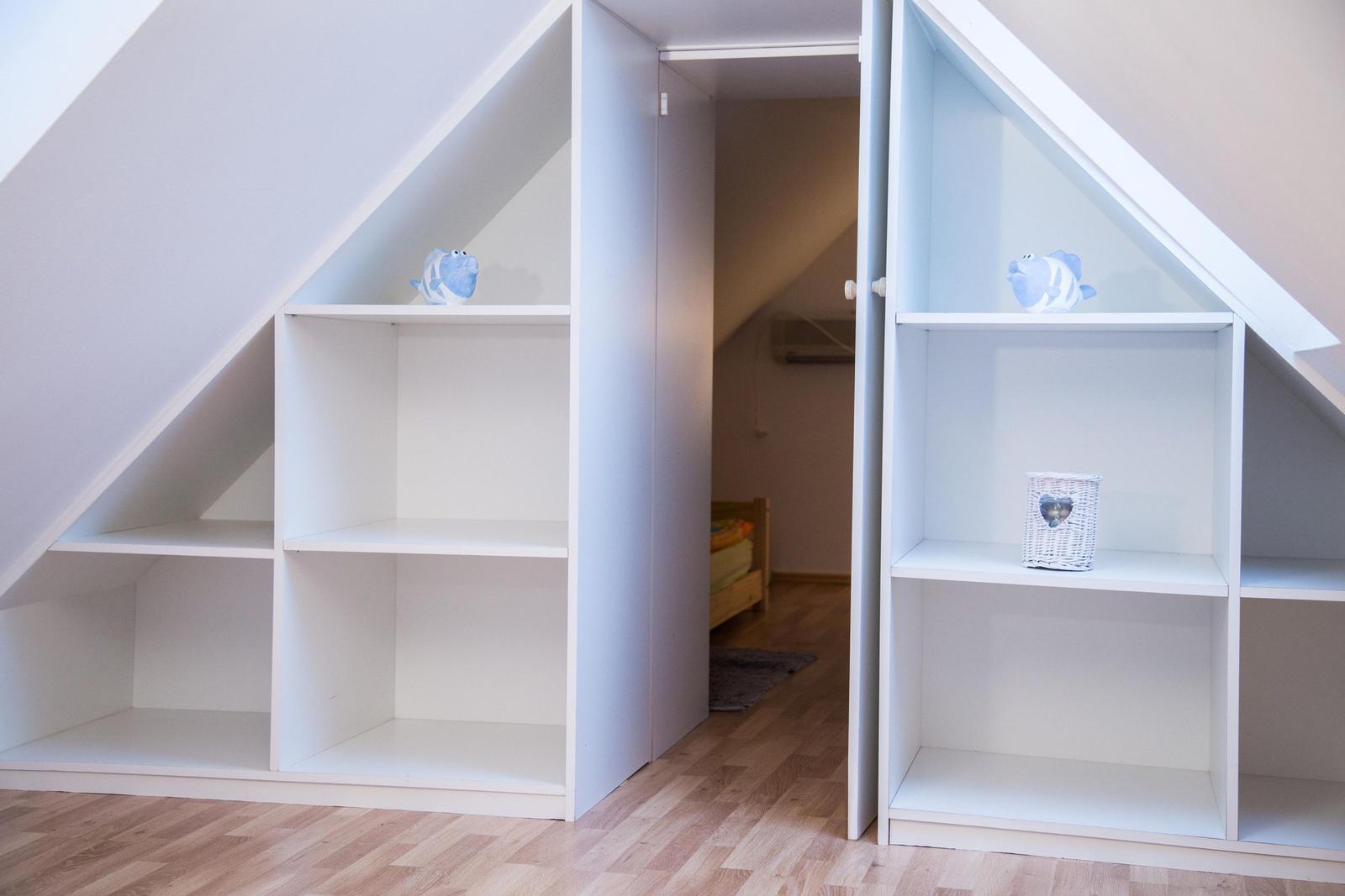 Zimmer mit Dachschränken und kleinem Bett im Hintergrund.