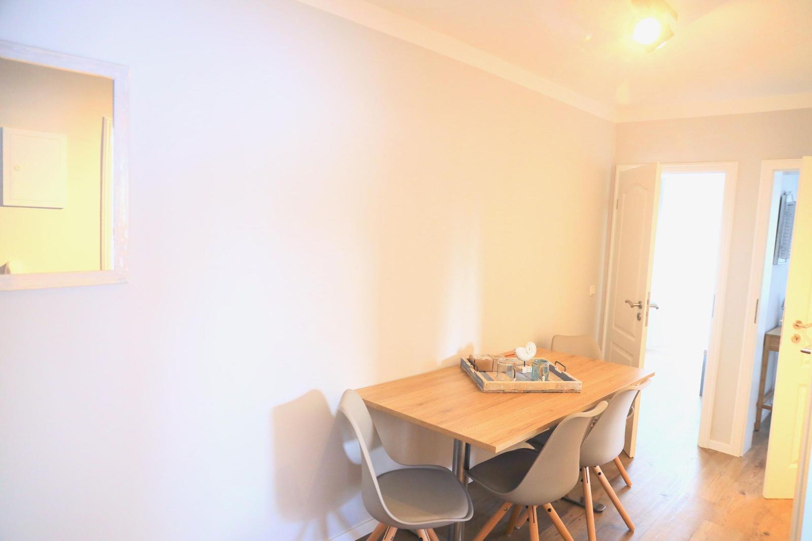 Essbereich mit Holztisch und Stühlen. Tisch mit Deko-Tablett. Helle Wände und Holzboden.