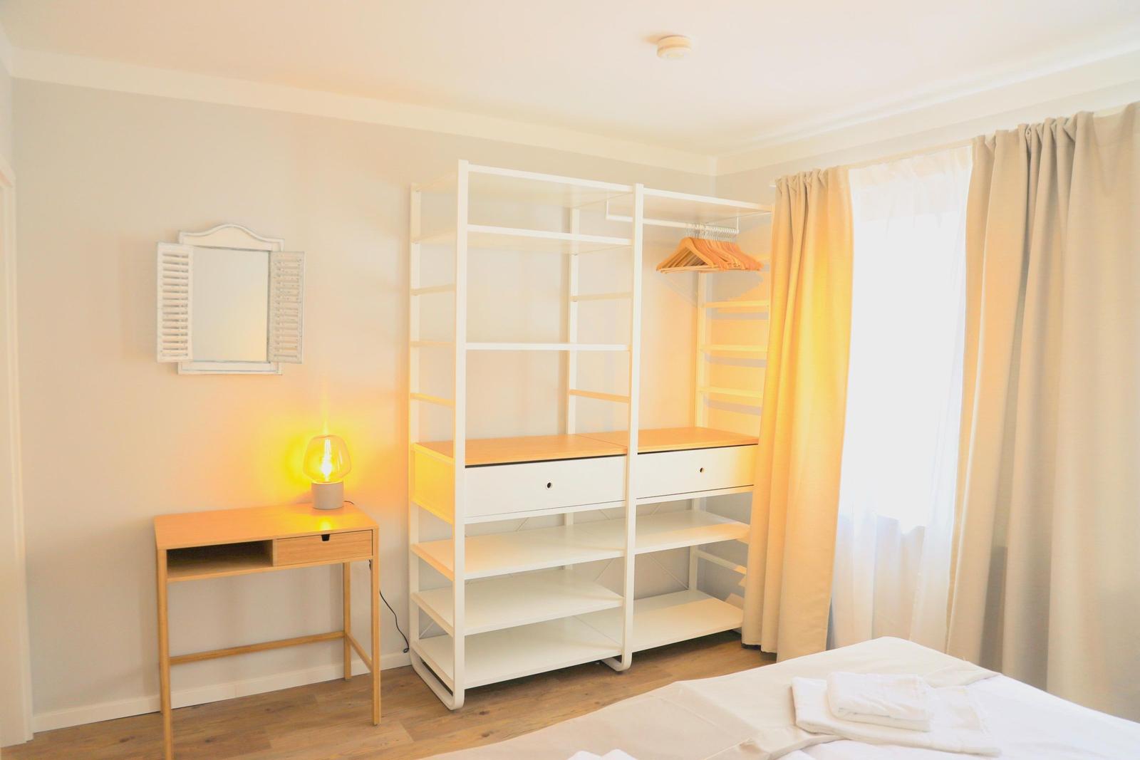 Schlafzimmer mit Schreibtisch, Kleiderschrank und Bett.