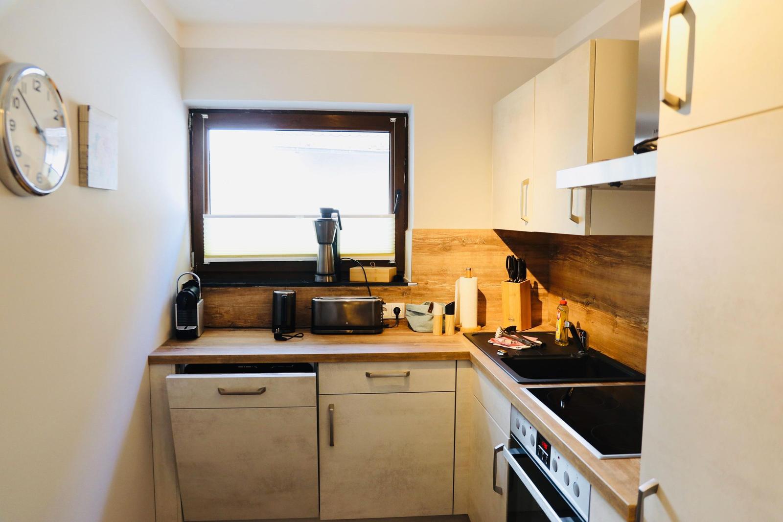 Küche mit Arbeitsplatte, Spüle, Herd und Fenster