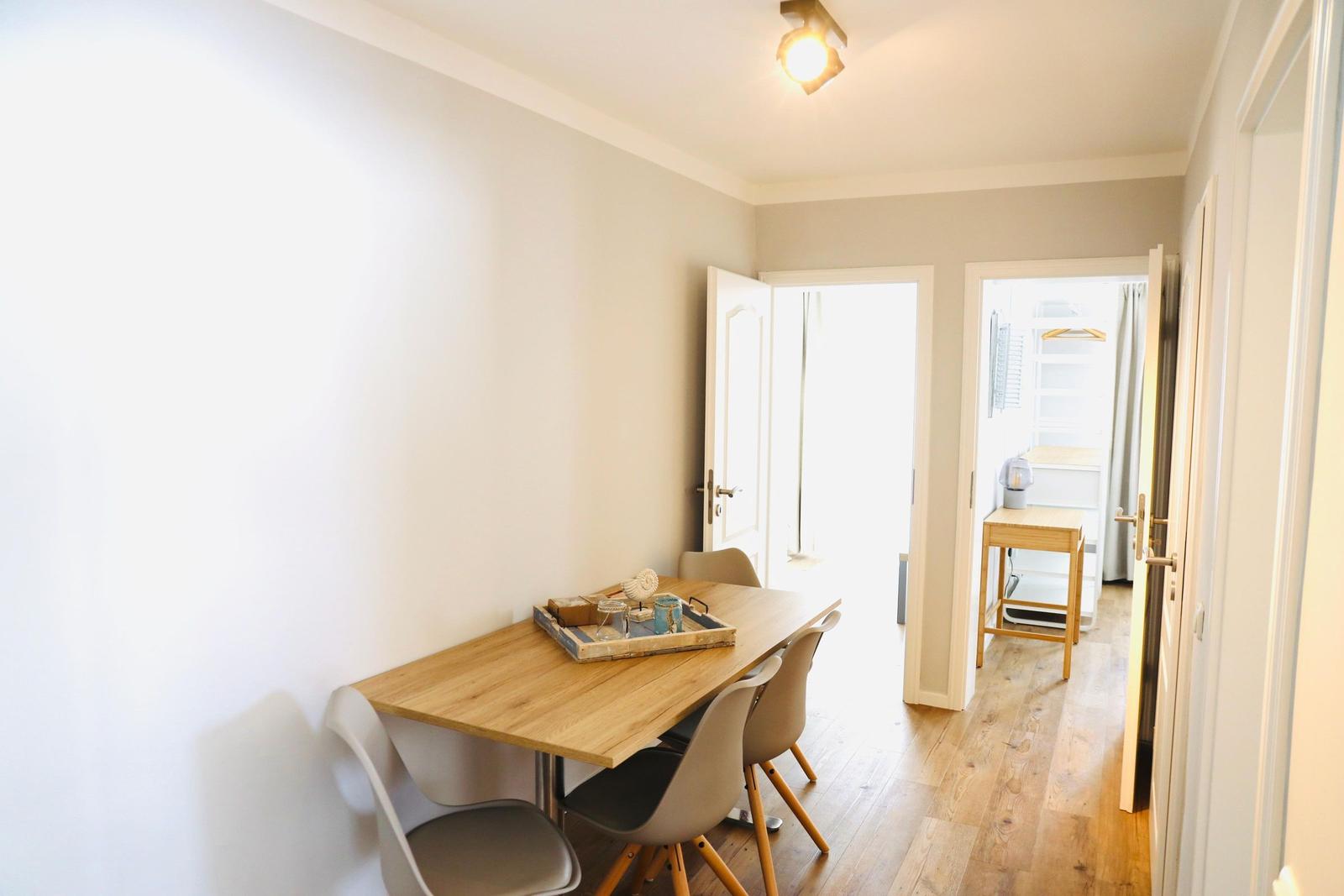 Essbereich mit Holztisch und Stühlen. Durchgang zu Schlafzimmer und Bad.