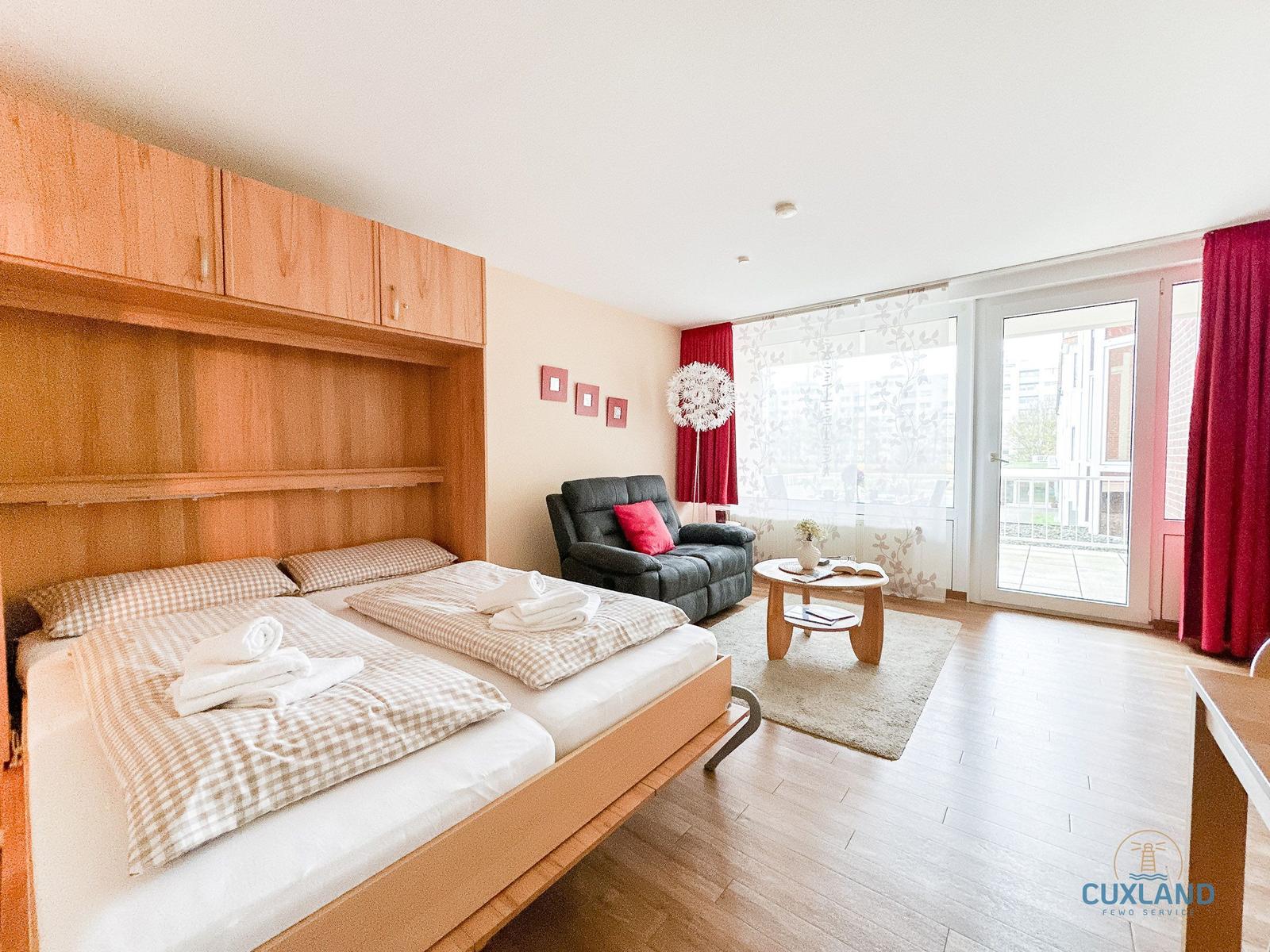 Schlafzimmer mit Bett, Sofa und Balkonzugang.