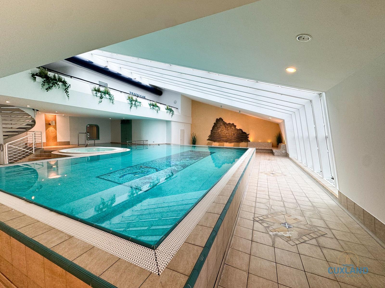 Innenpool mit Whirlpool und Dachfenster. Fliesenboden und Wanddekoration.