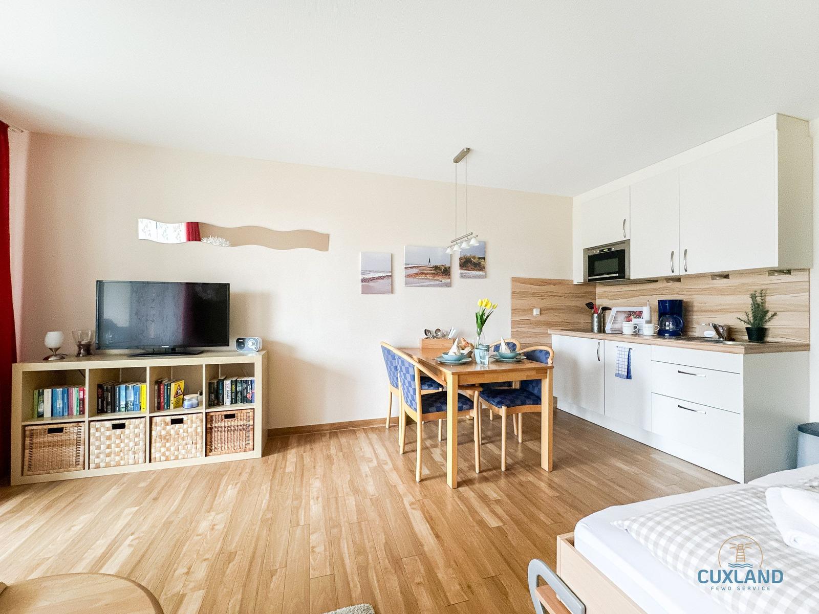 Wohnküche mit Esstisch, TV und Schlafbereich. Moderne Einrichtung und Holzboden.