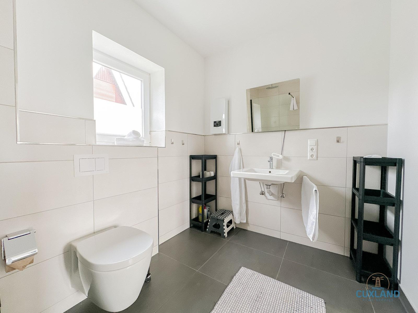 Badezimmer mit Toilette, Waschbecken und Fenster.