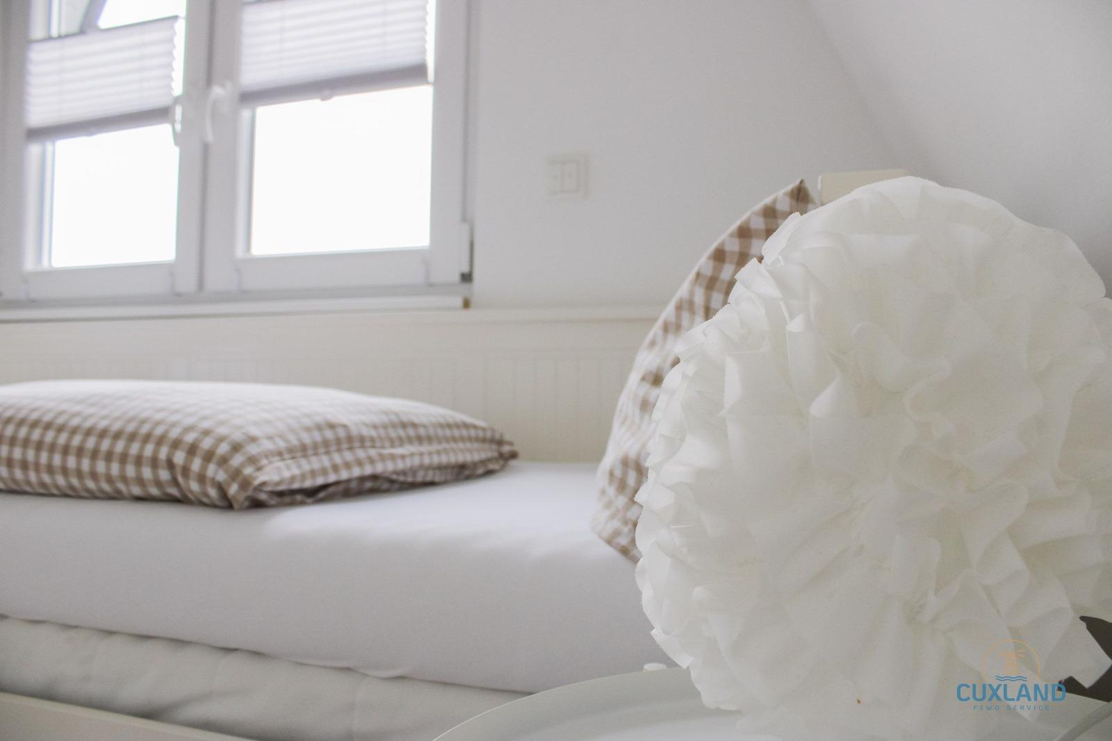 Schlafzimmer mit Bett, Fenster und dekorativer Deckenlampe.