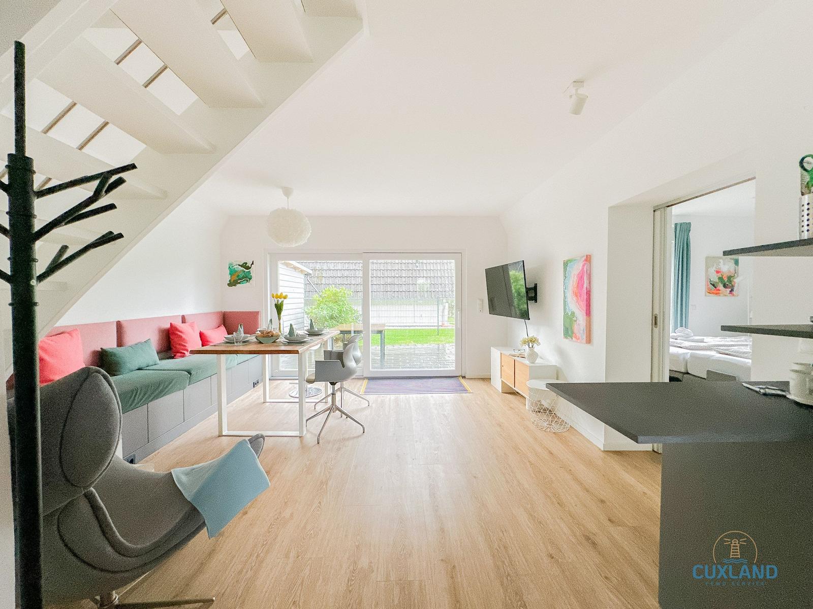 Wohnbereich mit Essbereich, Schlafzimmer und Küche. Holzboden und große Fenster.