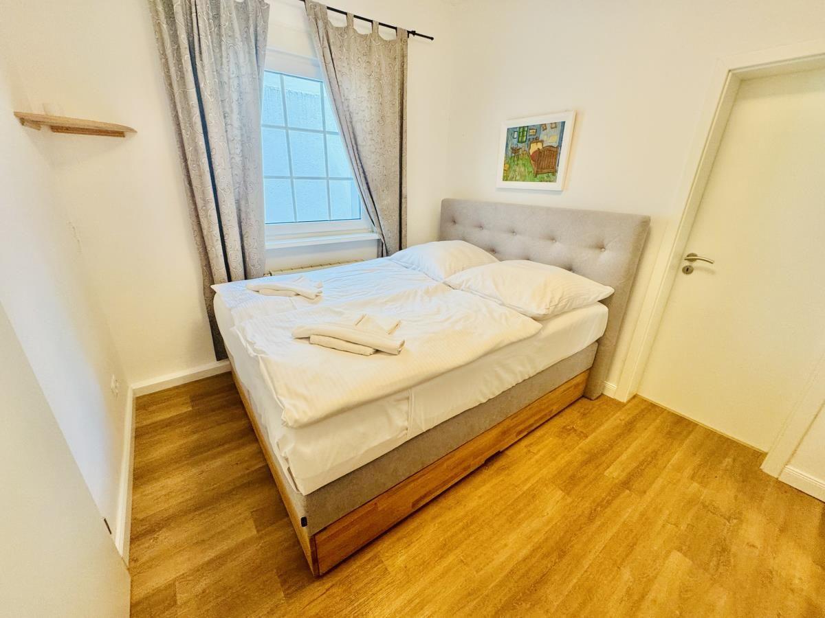 Schlafzimmer mit Doppelbett, Holzboden und Fenster mit Vorhängen.