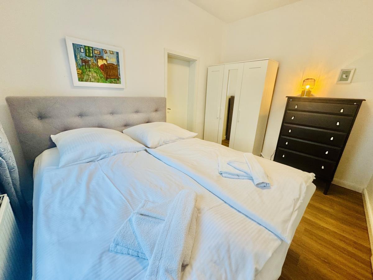 Schlafzimmer mit Doppelbett, Kleiderschrank und Nachttisch mit Lampe.