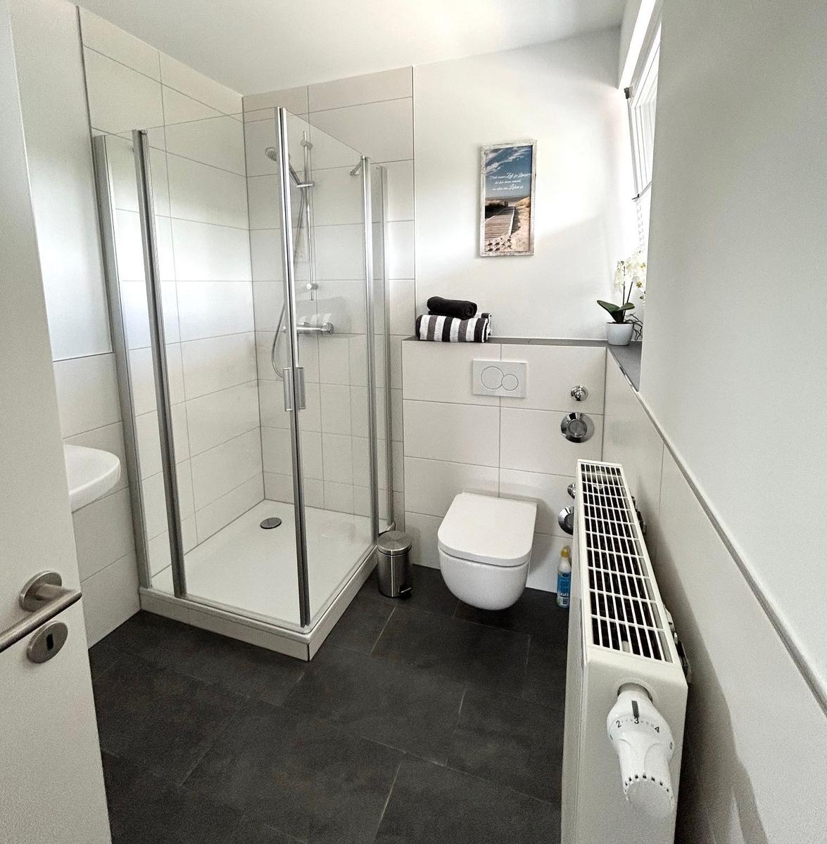Badezimmer mit Dusche, WC und Waschbecken. Bodenfliesen und Wandfliesen.