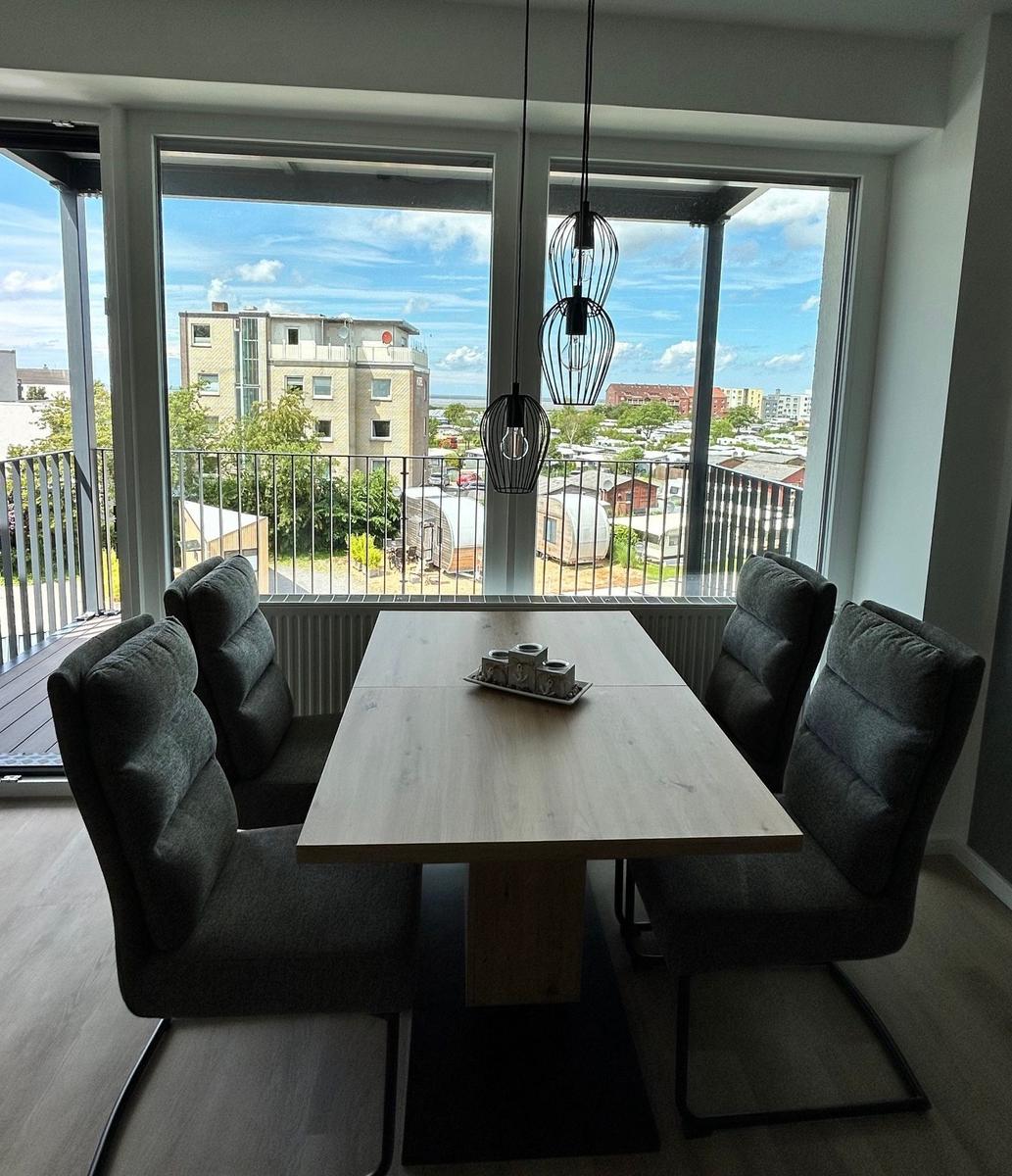 Esszimmer mit Tisch und Stühlen, Blick auf Balkon und Stadt.