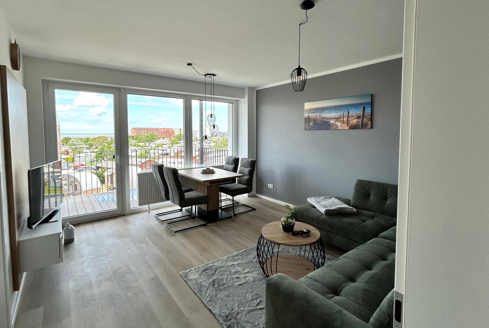 Wohn- und Essbereich mit Balkon, Sofa, Tisch und Fernseher.