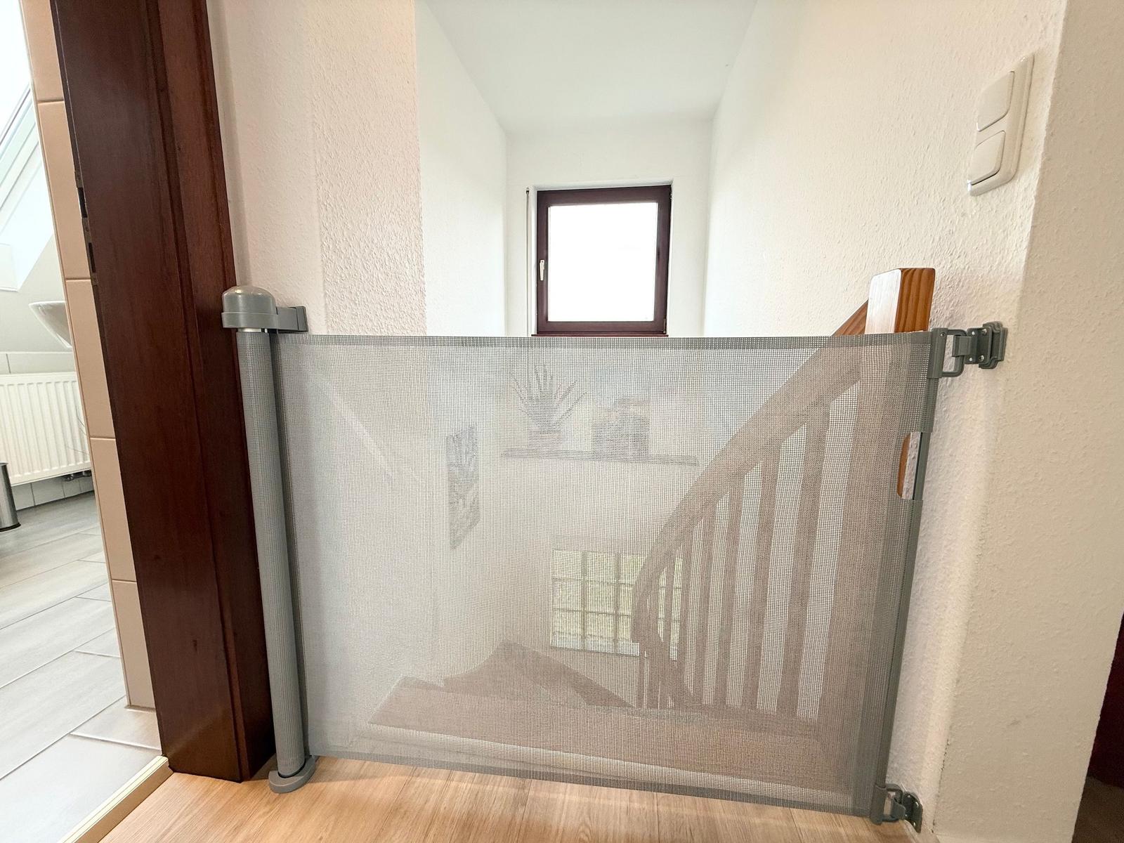 Child safety gate at staircase with window in background